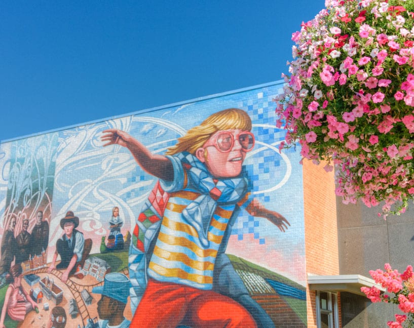 A mural of a little boy running with a blanket as a cape.