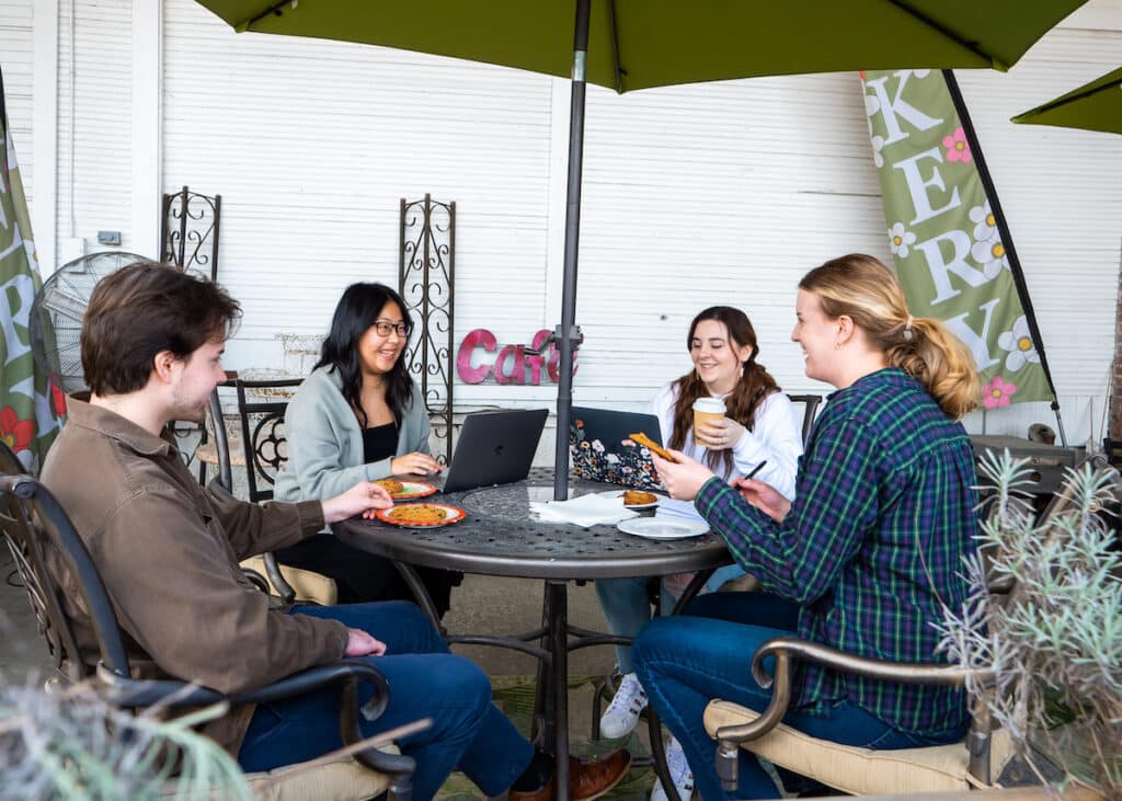 A group of friends or co-workers are working from the patio at Patti Cakes.