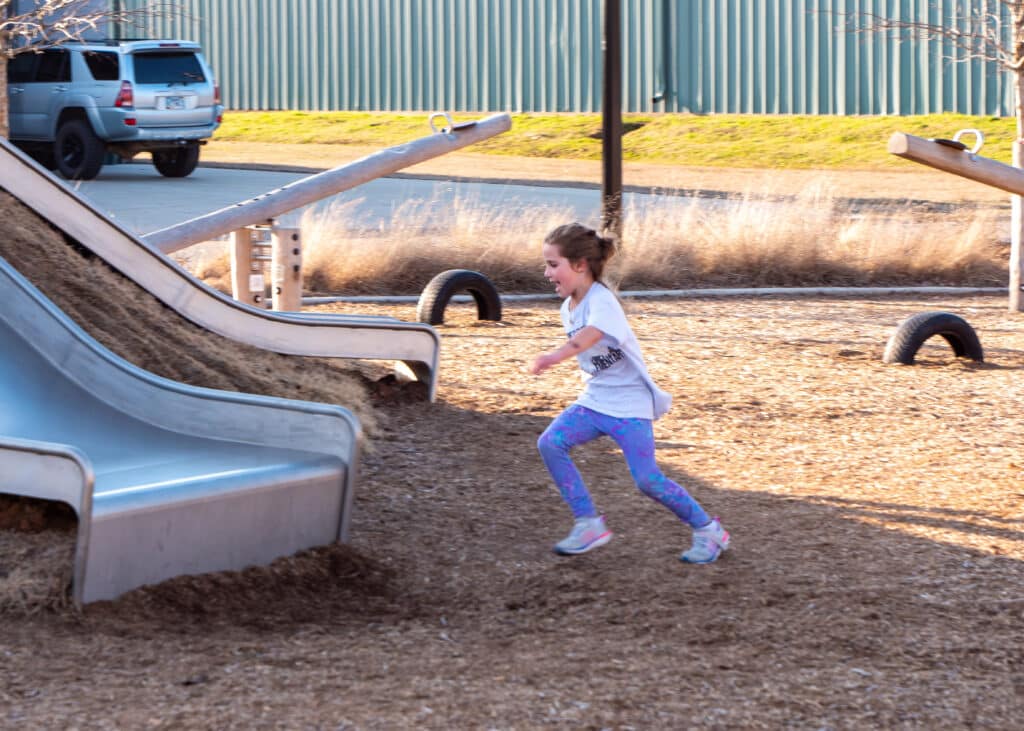 A young girl is running in a playground.