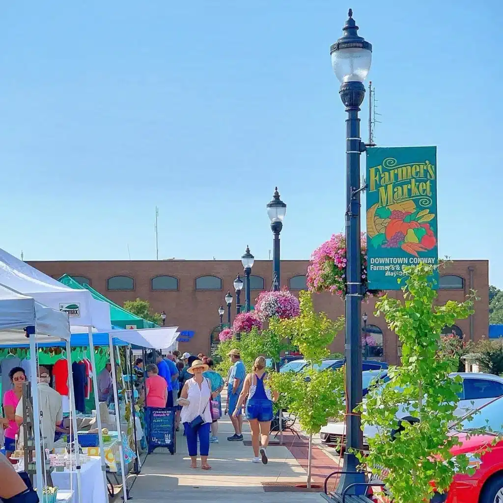 The Downtown Conway Farmer's market with people walking down the sidewalk.