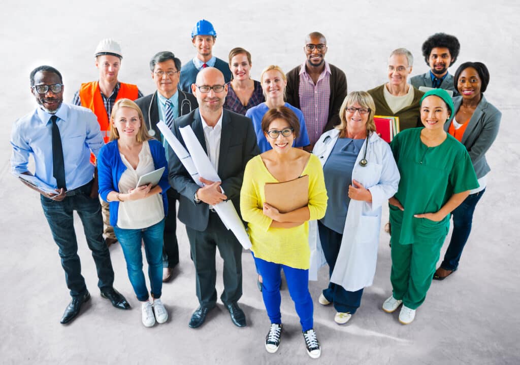 A group of diverse people with different jobs standing and smiling.