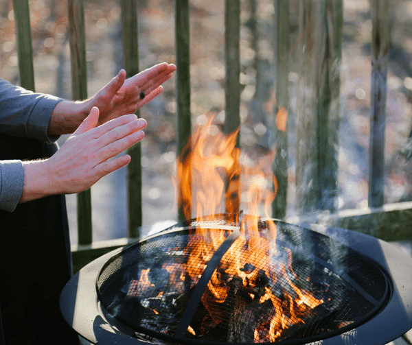 A person warms their hands over a fire pit.